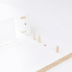 Nahaufnahme der weißen Flat-Pack-Teile mit Holzdübeln und Spanplattenkanten - perfekt für den Aufbau der KraftKids Wickelaufsatz weiß, passend für 160 cm breite HEMNES Kommode mit Blende, gerade Ausführung.