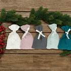 Fünf kleine KraftKids Adventskalender Musselin goldene Punkte Grün Grau Rosa Weiß Stoffsäckchen mit Bändern sind auf Holz arrangiert, akzentuiert durch immergrüne Zweige und rote Beeren mit Schnee bestäubt - ein bezaubernder Weihnachtsschmuck.