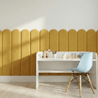 Ein minimalistisches Kinderzimmer mit einem kleinen weißen Schreibtisch, einem hellblauen Stuhl, Holzspielzeug und Buntstiften. An der Wand hängt der KraftKids Wandpaneel abgerundet Doppelkrepp in Senfgelb, der diesem modernen Raum eine gemütliche Note verleiht.