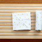 Eine Babydecke für Babyschale Sommer Musselin mit gelben Zitronen von KraftKids liegt dekorativ auf einer Holzoberfläche.