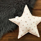 Das KraftKids Sternkissen Musselin Kirschen mit seinem süßen Kirschenmotiv liegt auf einem Holzboden neben einem grauen Fellteppich - ideal, um jedem Kinderzimmer Charme zu verleihen.