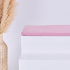 Eine hohe geflochtene Vase mit Pampasgras steht neben einem weißen Stufenpodest mit der KraftKids GmbH Sitzauflage für Ikea TROFAST Musselin rosa, alles vor einem schlichten hellen Hintergrund.