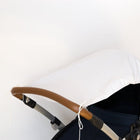 Nahaufnahme eines Kinderwagens mit braunem Griff und aufgesetztem Sonnenschirm KraftKids Sonnensegel Karo grau vor einem schlichten weißen Hintergrund.