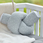 Die KraftKids Wickeltischumrandung Musselin grau Pusteblumen ruht auf einer weißen gepolsterten Bank neben einer cremefarbenen Decke, mit Grünzeug im Hintergrund.