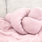 Ein weiches, rosafarbenes Knotenkissen liegt auf dem KraftKids Wickeltischumrandung Doppelkrepp Rosa vor einem hellgrauen Betonwandhintergrund.