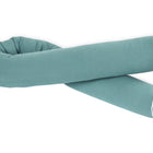 Eine lange, zylindrische KraftKids Wickeltischumrandung Musselin nilblau mit weißer Paspelierung an den Enden, locker gekreuzt vor weißem Hintergrund.