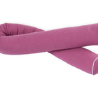 Das KraftKids Wickeltischumrandung Musselin purpur ist ein langes, zylindrisches lila Körperkissen mit weißer Paspelierung entlang der Nähte, dargestellt in einer lockeren, gekreuzten Position auf weißem Hintergrund.