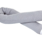 Eine graue U-förmige Wickeltischumrandung Musselin grau Punkte von KraftKids, mit kleinen weißen Punkten, die in der Mitte mit weißen Stoffenden gekreuzt sind, isoliert auf einem weißen Hintergrund.