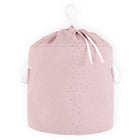 Der KraftKids Spielzeugkorb Musselin goldene Punkte auf Rosa hat einen rosafarbenen Stoff mit goldenen Punkten, zwei weiße Seitengriffe und einen weißen Kordelzug - perfekt für die Aufbewahrung von Spielzeug im Kinderzimmer, hier vor einem weißen Hintergrund.