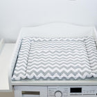 Ein KraftKids Wickelaufsatz für Waschmaschinen und Trockner mit grauer und weißer Chevron-Wickelauflage steht auf einer Waschmaschine und bildet eine praktische Wickelstation vor weißem Hintergrund.